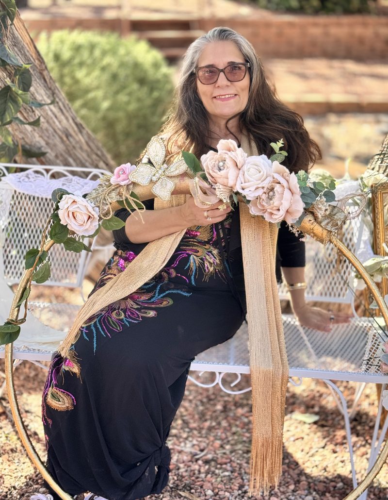 Sharon Shapiro seated among flowers in a golden hoop